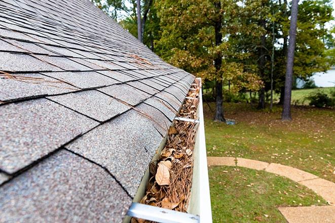 worker cleaning and maintaining gutters to prevent blockages